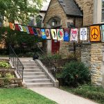 Sts. Luke and James red front door with peace flags hung up on a string across the front yard. 